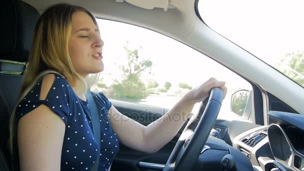 Filmagem em câmera lenta de uma jovem mulher feliz dirigindo carro e cantando — Vídeo de Stock