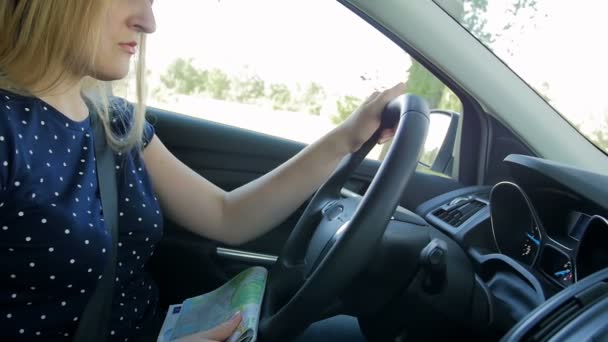 Lassított felvétel, fiatal nő, autó vezetés, és a papír térképet néztem. Női vezető eltévedt az ismeretlen út — Stock videók