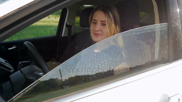 Vídeo em câmera lenta de mulher sorrindo beatiful abaixando janela do carro e olhando para a câmera — Vídeo de Stock