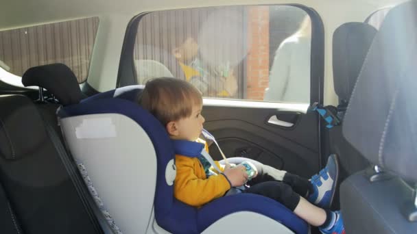 4k video of adorable baby boy sitting in child car safety seat — Stock Video