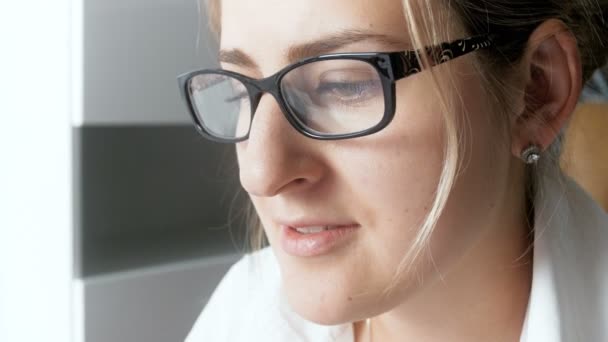Съемки крупным планом 4k красивой деловой женщины в очках, разгуливающей в офисе и печатающей на компьютере — стоковое видео