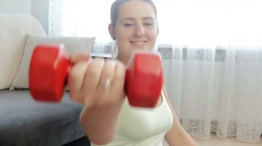 Closeup genç kadın dumbbells ile oturma odasında egzersiz 4k video