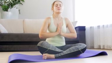 Güzel genç kadın meditasyon ve yoga fitness mat oturma odası, pratik