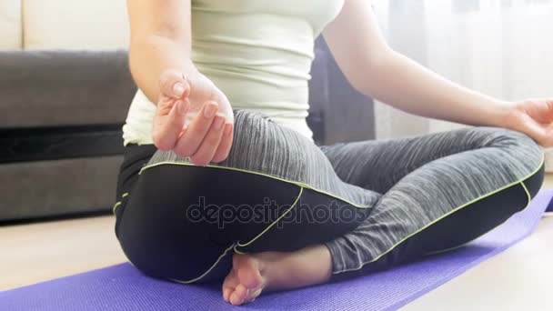 Primer plano imágenes de muñecas 4k de manos femeninas sentadas en yoga loto posan en colchoneta de fitness — Vídeos de Stock