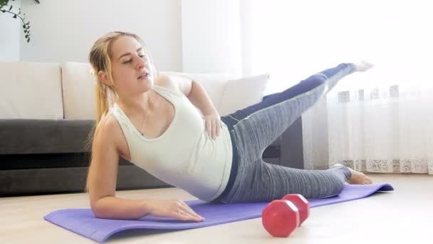 4k video de la hermosa mujer joven haciendo ejercicio en la colchoneta de fitness en casa — Vídeos de Stock