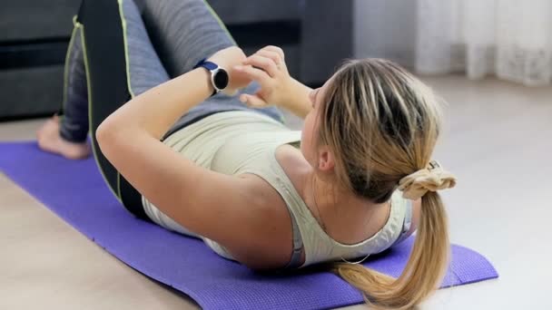 Imágenes en cámara lenta de una mujer joven colocando sus relojes inteligentes antes de hacer ejercicio en casa — Vídeos de Stock