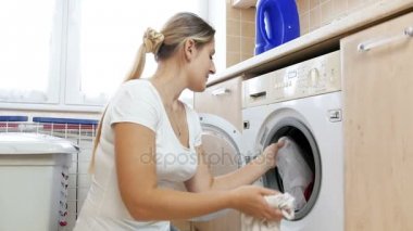 4 k video genç kadının birlikte çamaşır makinesine farklı renk giysiler koyarak hata yaptım