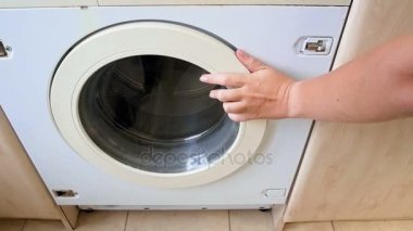 Ağır çekim görüntüleri genç kadının çamaşır maching açar ve giysileri içinde atar