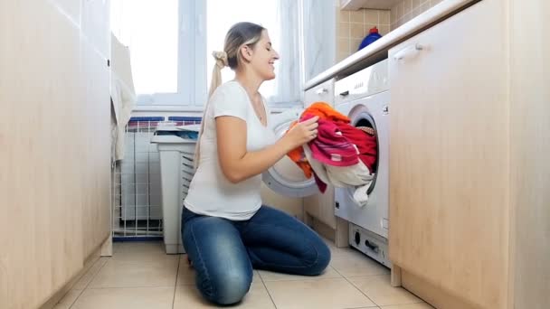 Imágenes en cámara lenta de la risa alegre ama de casa divirtiéndose en la lavandería y tirar ropa — Vídeo de stock