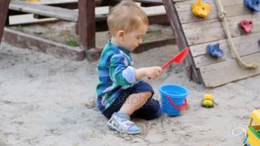 Sandbox parkında oynayan sevimli yürümeye başlayan çocuk Slow motion video