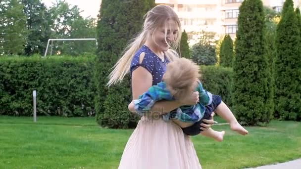 慢动作视频快乐美丽的母亲举行和纺纱与她的蹒跚学步的儿子在公园 — 图库视频影像