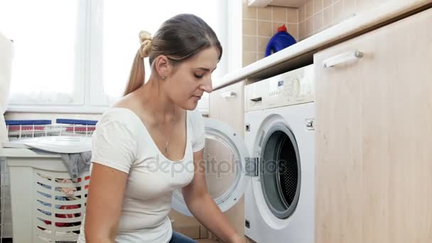 若い主婦の洗濯をして、洗濯機に汚れた服を投げの 4 k 映像 — ストック動画