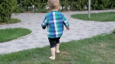 Hareketli video sevimli yalınayak küçük çocuk patika üzerinde çalışan yavaş ve Parkı'nda çim
