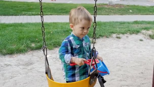 Imágenes en cámara lenta de lindo niño de 2 años jugando con arena en el parque — Vídeos de Stock