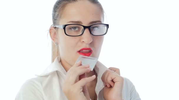 Nahaufnahme Zeitlupenvideo von sexy Frau mit rotem Lippenstift, die Kondom im Mund hält — Stockvideo