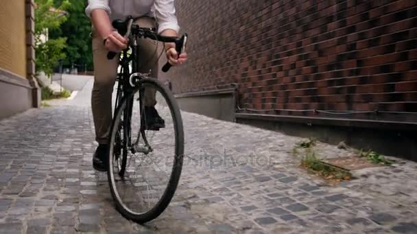 4k steadicam vídeo of young man riding bike on old narrow street — Vídeo de Stock