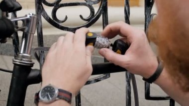 Bisikletine sokakta korumak için şifreli kilit ve zincir kullanan genç adam görüntülerini closeup 4k