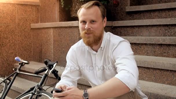 4k portrait of happy smiling red bearded hipster man sitting on staircase — Stock Video