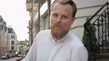 Kameraya bakarak beyaz gömlek giymiş Küpeli adam kırmızı gülümseyen portresi sakallı