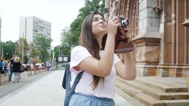 Vidéo 4k de fille brune souriante faisant des photos sur caméra de film rétro — Video
