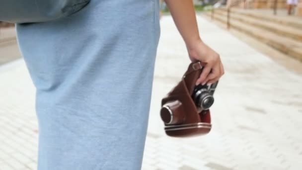 Nahaufnahme in Zeitlupe: junges Touristenmädchen läuft mit Vintage-Kamera auf der Straße — Stockvideo