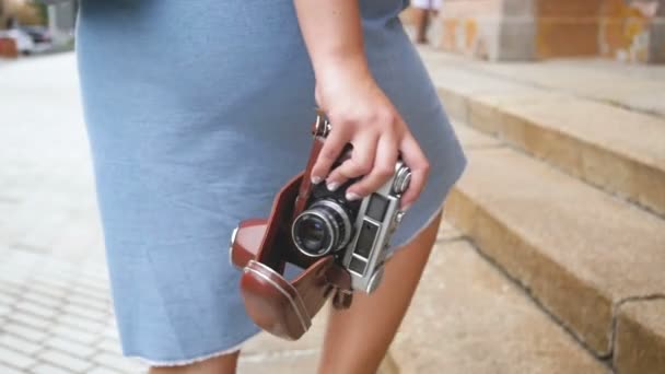 Cámara trasera de cámara lenta video de una mujer joven sosteniendo la cámara manual vantage subiendo las viejas escaleras de piedra — Vídeos de Stock