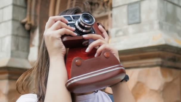 Slow motion video of beuatiful smiling tourist girl making photographs of city on old fil camera — Stock Video