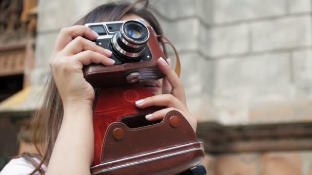 Closeup slowmotion portret van lachende jong meisje poseren met vintage filmcamera op straat — Stockvideo