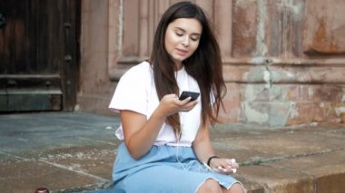 Sokak ve dinleme müzik üzerinde oturan uzun saçlı güzel esmer kadının Slow motion video