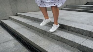 Atlama ve taş merdivenle sokakta çalışan spor ayakkabıları şık kız closeup ağır çekim görüntüleri