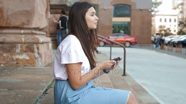 Slow motion séquences de fille brune mignonne écouter de la musique sur la rue — Video