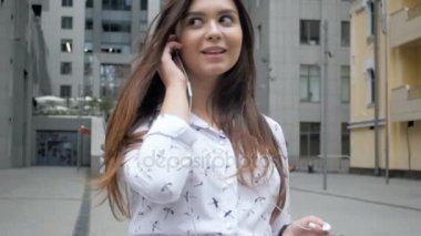 Sokakta yürürken müzik üstünde hareket eden telefon dinleme genç kadın gülümseyerek, Closeup ağır çekim görüntüleri