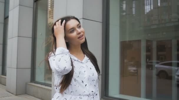 Slow motion video av glada leende kvinna med långt hår går på gatan på blåsig dag — Stockvideo