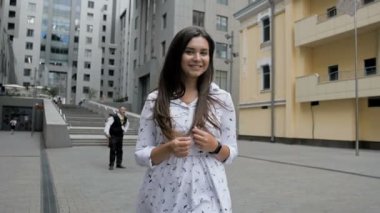 Sokakta yürüyen ve uzun saçlı oynarken mutlu gülümseyen kız ağır çekim görüntüleri