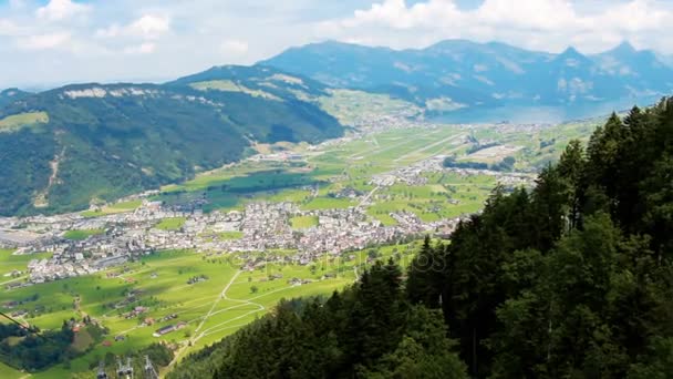 Аэросъемка красивых высоких гор, покрытых деревьями в солнечный день в швейцарских Альпах — стоковое видео