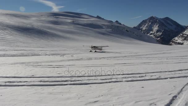 Aufnahmen von kleinen Privatflugzeugen, die auf einem Gletscher in den Bergen landen — Stockvideo