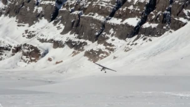 Кадри невеликого приватного літака, що злітає зі снігової злітно-посадкової смуги на льодовику в горах — стокове відео