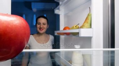 4 k görüntüleri buzdolabı içinde seyir ve Kırmızı elma ısırma güzel youing kadın