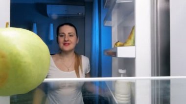 buzdolabı raf yeşil sulu elma alarak ve bu ısırma güzel gülümseyen kadın 4 k görüntüleri