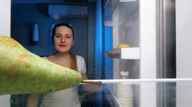 4 k closeup görüntülerini alarak ve buzdolabı gelen taze sulu armut geceleri ısırma gülümseyen güzel kadın