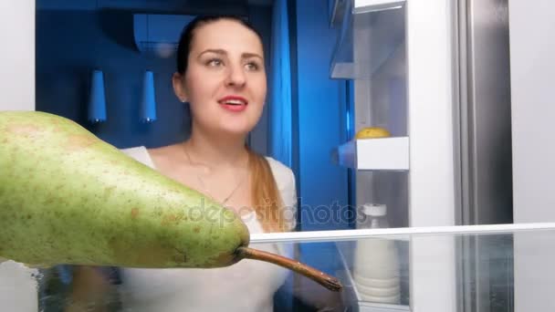 Zbliżenie 4k materiał z piękną kobietą, patrząc wewnątrz lodówki i jeść soczyste gruszki — Wideo stockowe