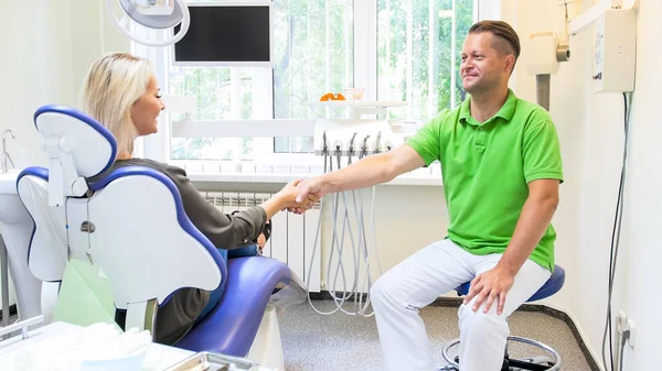 Uśmiechnięty mężczyzna dentysta uścisk dłoni z jego pacjenta po zabiegu zęby — Zdjęcie stockowe