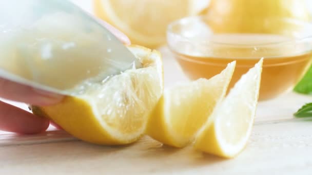 Closeup 4k vídeo of female hand cutting fresh lemons for lemonade on white wooden desk — Vídeo de Stock