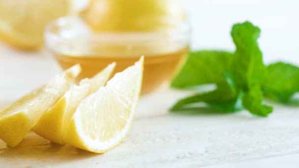 4k video van vers gesneden citroenen, mes en ingrediënten voor limonade op witte houten bureau pannen — Stockvideo
