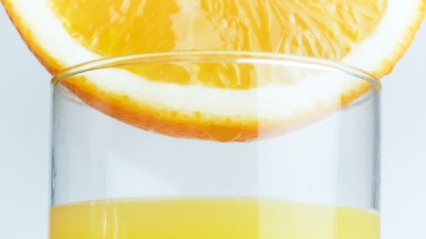 Imágenes Macro 4k de gotitas de jugo que caen en vidrio de rodajas de naranja — Vídeos de Stock