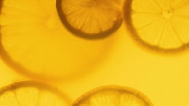 4k closeup video of backlit lemon slices floating in orange juice in jar — Stock Video