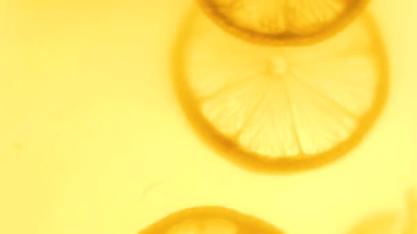 Closeup 4k πλάνα του Περιστρεφόμενη φέτες λεμονιού σε φρέσκο χυμό — Αρχείο Βίντεο