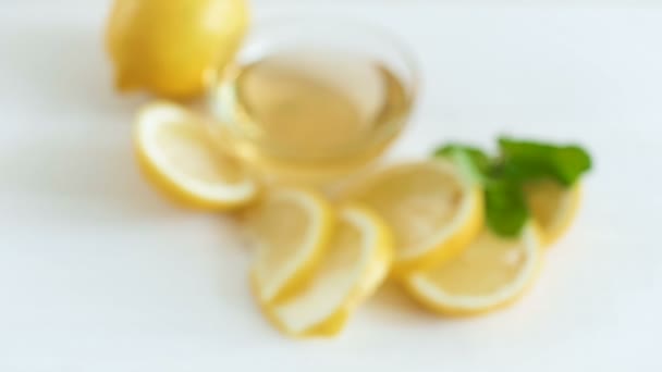 Camera zooms and focuses on lemons with honey lying on white wooden table — Stock Video