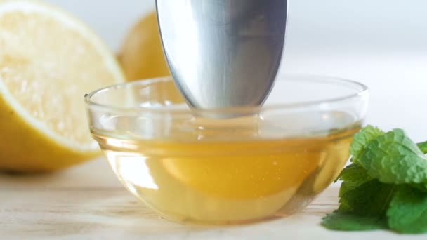 Primo piano filmato al rallentatore di immergere cucchiaio di metallo in vaso con miele d'api naturale — Video Stock