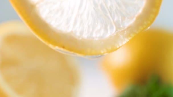 Vértes lassított felvétel, csepp, lassan csöpög oldaláról szelet citrommal — Stock videók